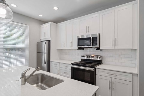 a white kitchen with black appliances and white cabinets